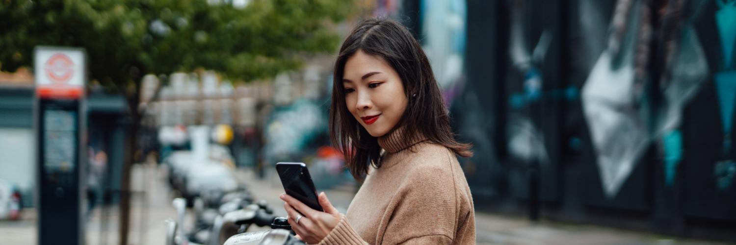 A woman next to electric bikes holding a mobile phone